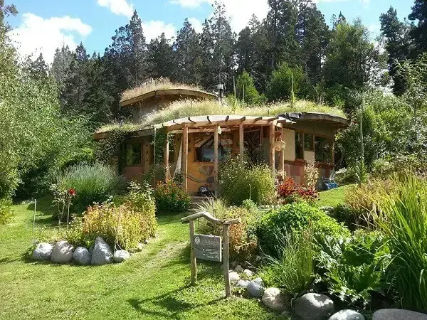 Bioconstrucción: casa con techo verde y vegetación circundante.