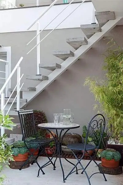 Jardim embaixo da escada externa: mesa e cadeira criam um espaço para receber visitas