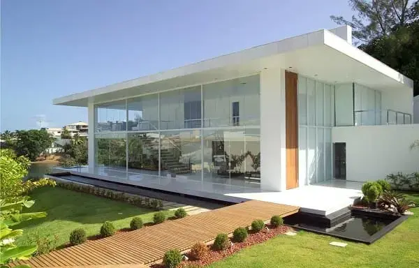 Fachadas de casas térreas modernas: fachada de vidro favorece a iluminação zenital (projeto: SQ+ Arquitetos Associados)