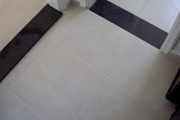 Soleira preta de granito em piso branco setoriza os ambientes