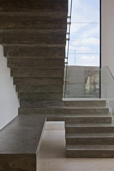 Escada de concreto em L com guarda-corpo de vidro (foto: Pinterest)