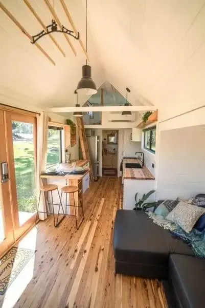 Tiny House com piso de madeira e sofá preto (foto: Pinterest)