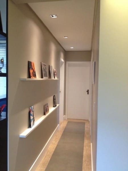 Parede de quadros: corredor com prateleiras e quadros pequenos (projeto: Ed Arquitetura)