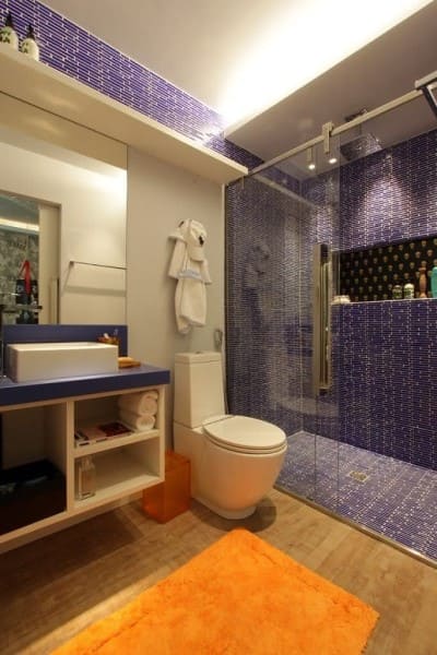 Cores complementares no banheiro: box azul e tapete laranja (foto: Viva Decora)