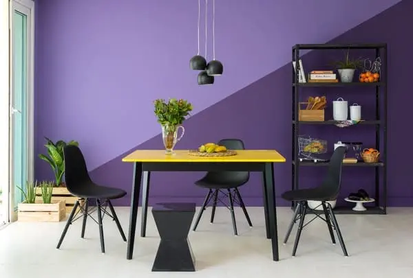 Cores complementares: parede roxa com pintura geométrica e mesa com tampo amarelo (foto: Mobly)