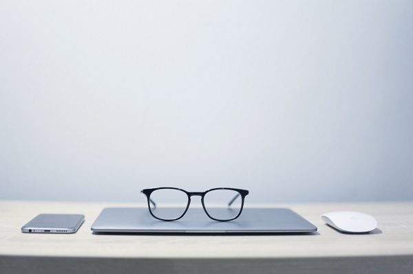 Imagem de mesa de trabalho com computador, smartphone e óculos