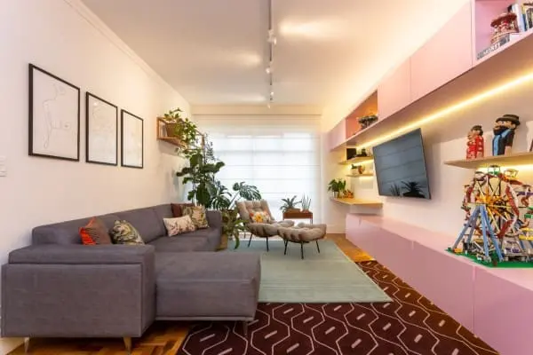 Sofá com estofado cinza e rack planejado rosa (projeto: Motirõ Arquitetos)