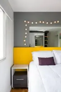 A cabeceira na cor Pantone 2021 amarela ilumina o dormitório de casal