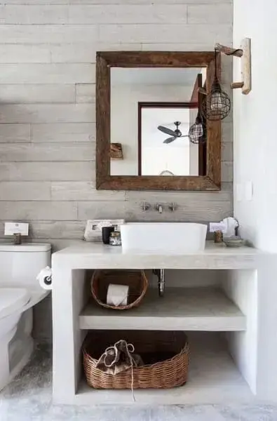Móveis de alvenaria: bancada de banheiro com concreto aparente e espelho com moldura de madeira (foto: Pinterest)