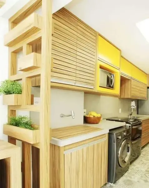 Cozinha linear com armários amarelos e eletrodomésticos pretos (foto: Simplichique)