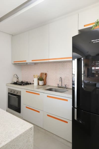1. Cozinha linear pequena com detalhes laranjas e geladeira preta (foto: Studio Canto Arquitetura)