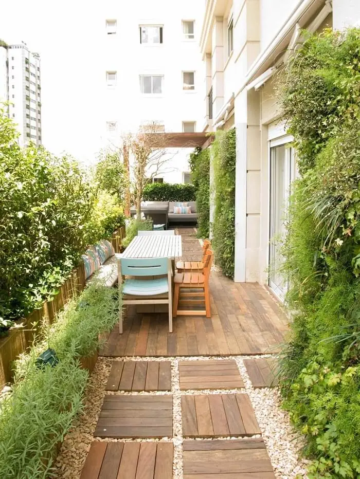 Área social do condomínio com pisante de madeira para jardim. Projeto de Gigi Botelho Paisagismo