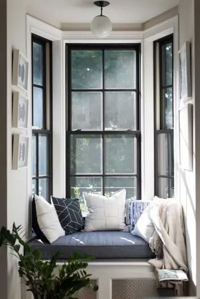 Bay Window com moldura preta, sofá e almofadas (foto: Decor Fácil)