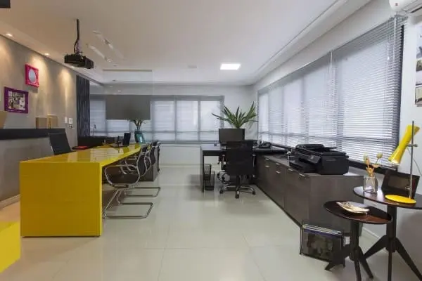 Cortina para escritório: persiana de alumínio clara e bancada amarela (foto: Natalia Pini)