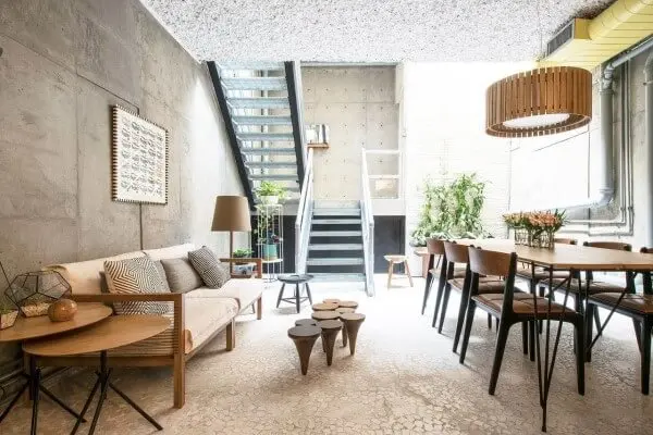 Casa de concreto com sofá estofado claro e cadeiras de couro marrom (foto: A.M Studio Arquitetura)