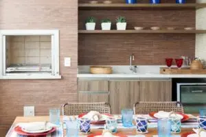 Tijolo refratário varanda gourmet com mesa de madeira e churrasqueira revestida com tijolo refratário projeto Sandra Picciotto