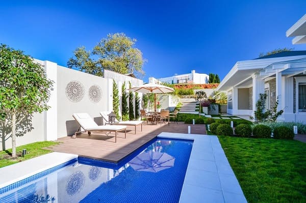 Piscina de concreto com espreguiçadeiras e grama foto Bender Arquitetura