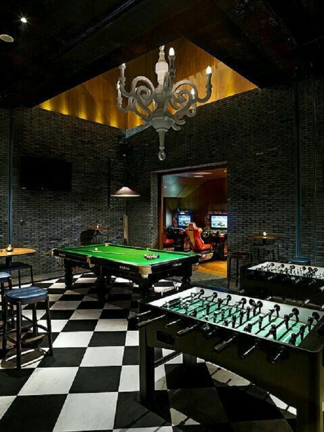 Sala de jogos com parede preta e pendentes metálicos