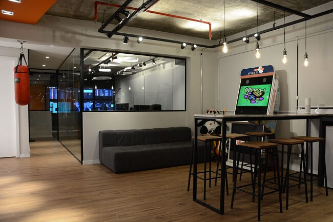 Sala de jogos simples com sofá estofado e banquetas modernas